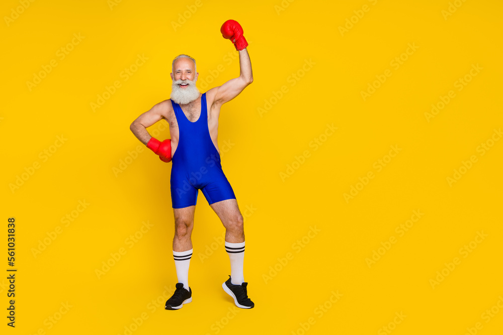 Full length photo of cool lucky senior guy wear blue overall costume rising fist boxing glove empty space isolated yellow color background