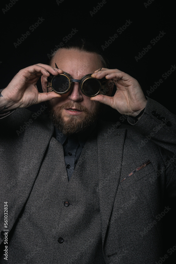 Obraz premium charismatic man in a classic suit and steampunk goggles on a black background stylish Portrait
