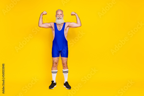 Full length photo of cheerful funky senior masculine man trainer demonstrate power stand empty space isolated on yellow color background