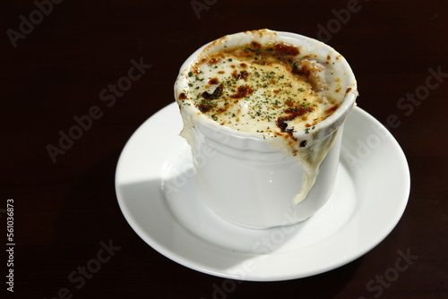 Cheesy French onion soup on a white cup and saucer