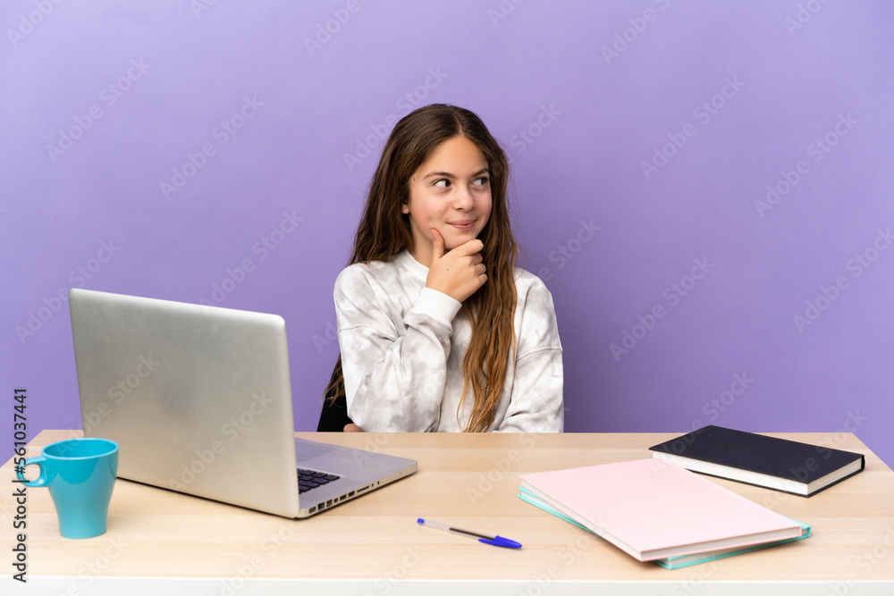 Little student girl in a workplace with a laptop isolated on purple background thinking an idea while looking up Little student girl in a workplace with a laptop isolated on purple background thinking an idea while looking up