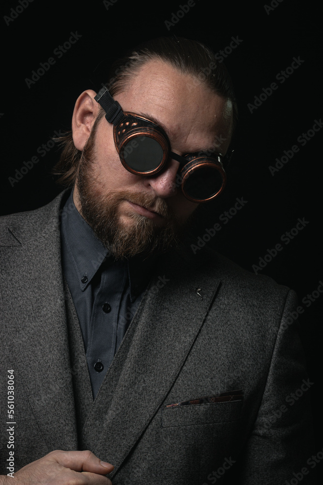 Obraz premium charismatic man in a classic suit and steampunk goggles on a black background stylish Portrait