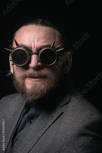 charismatic man in a classic suit and steampunk goggles on a black background stylish Portrait