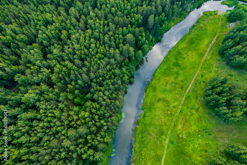 drone view of a river bend in a forest area, the banks are covered with grass