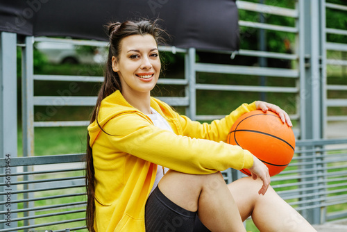 Beautiful girl with basketball on bench during break. Hobby and sport concept.
