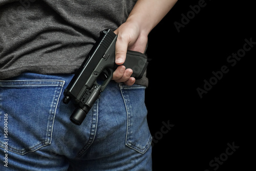 A man holding a gun in his hand behind his back, close-up view. crime, attempted murder, a gunshot wound, the killer, robbery