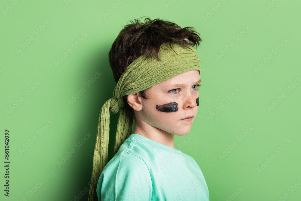 Boy with strips on cheeks against green background Boy with strips on cheeks against green background
