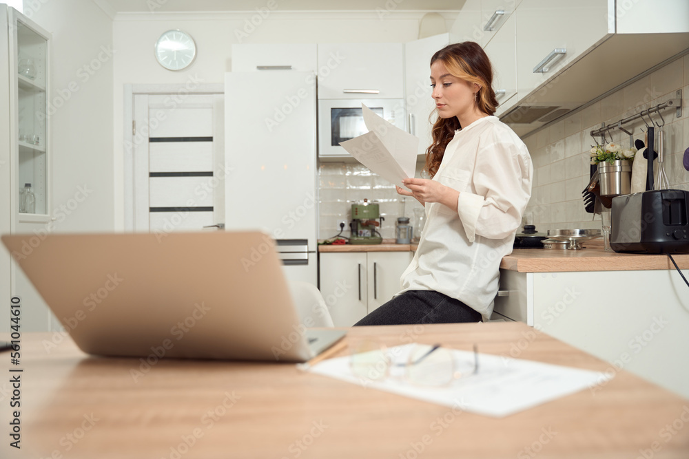 Focused female looking through documents at home Focused female looking through documents at home