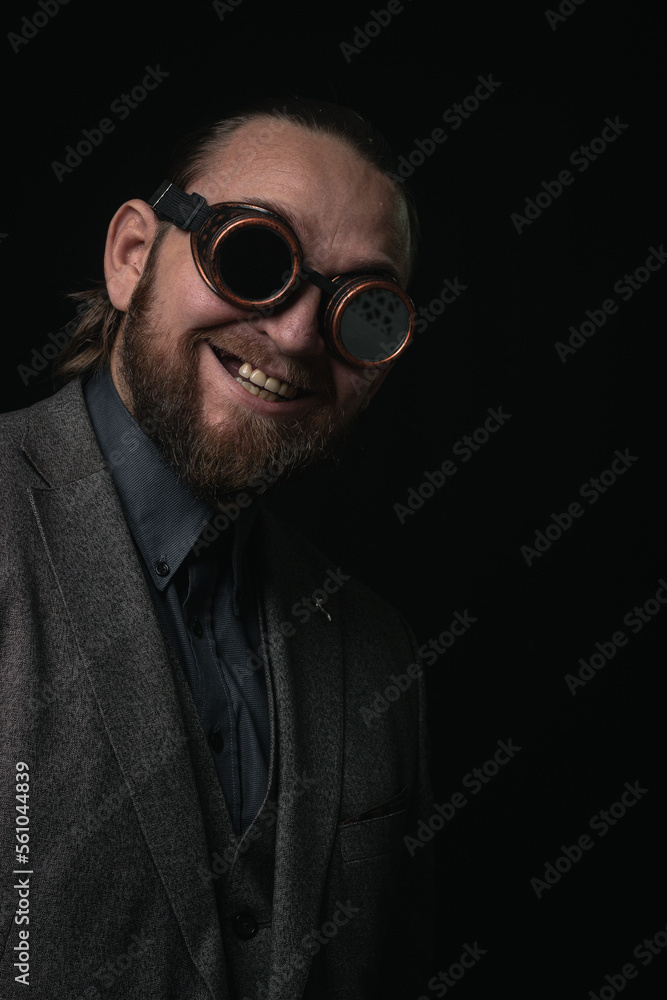 Obraz premium charismatic man in a classic suit and steampunk goggles on a black background stylish Portrait