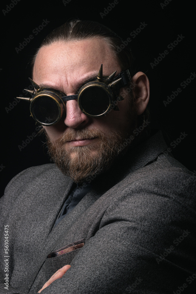 Fototapeta premium charismatic man in a classic suit and steampunk goggles on a black background stylish Portrait