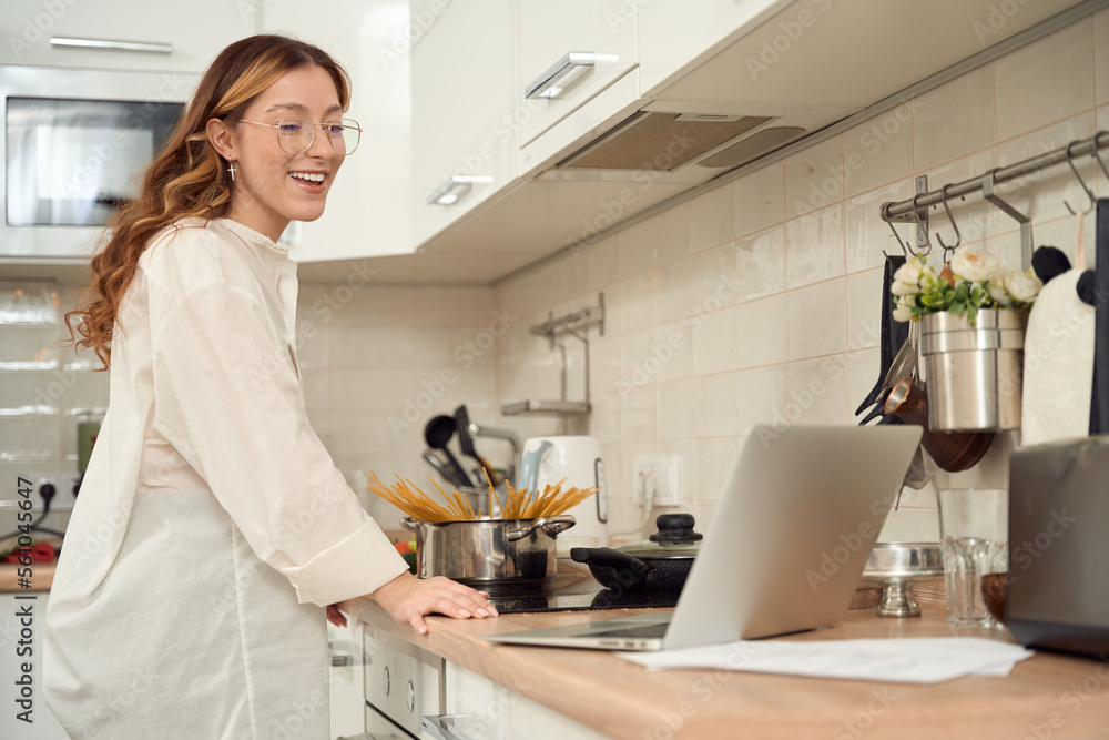Cheerful housewife reading online recipe before cooking