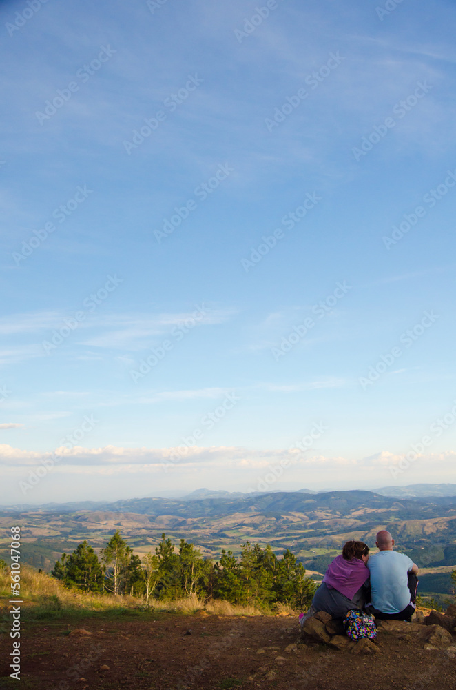 Young couple sitting on the top of the mountain on a sunny summer day