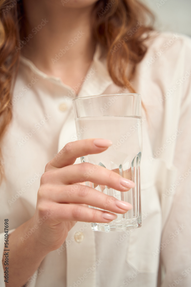 Caucasian woman is consuming mineral water indoors Caucasian woman is consuming mineral water indoors