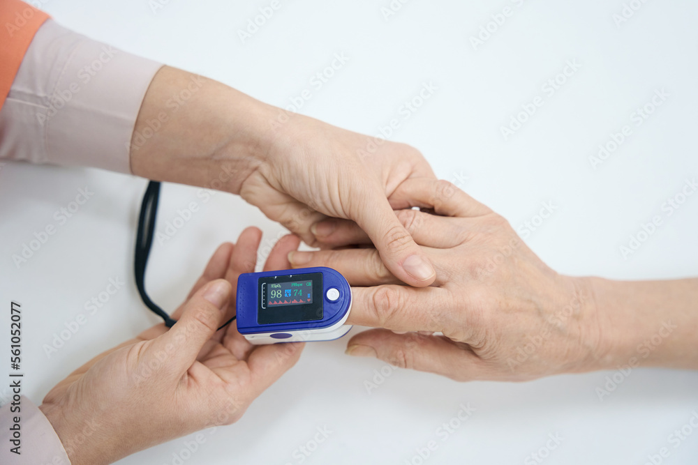 Nurse attaches a pulse oximeter to the patient finger Nurse attaches a pulse oximeter to the patient finger