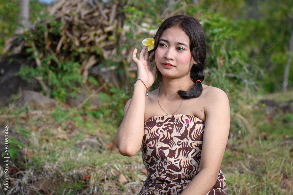 Portrait girl with long hair and a flower behind her ear in classic shoulder loose-fit clothes with ponytails Portrait girl with long hair and a flower behind her ear in classic shoulder loose-fit clothes with ponytails