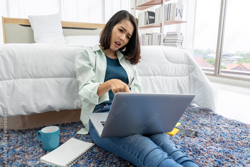 Naklejka premium Asian woman working at bedside in bedroom at home with her tablet