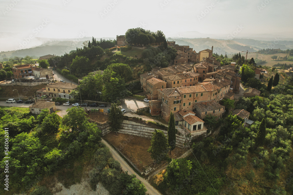 Fototapeta premium Small village of Chiusure on top of the hill surrounded by Karst cliffs landscape photographed with a drone. Toscana, Tuscany, Asciano, province of Siena in Italy with a little mud road 06.16.2021