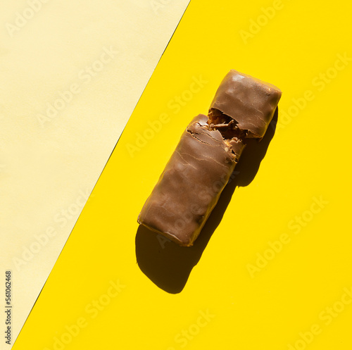 broken protein bar in hard sunlight, top view on yellow background