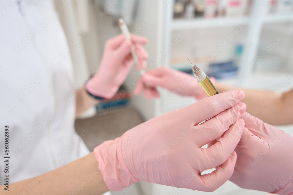 Assistant gives the doctor a syringe with medicine Assistant gives the doctor a syringe with medicine