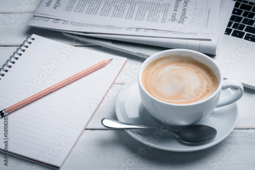 Black cup of coffee, notebook, newspaper and laptop on the table, morning news. get ready for work in the morning
