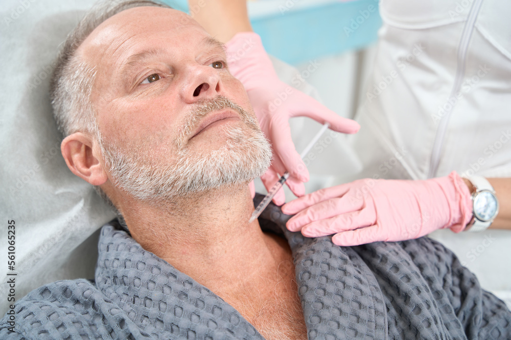 Nurse in protective gloves makes an injection in patient neck Nurse in protective gloves makes an injection in patient neck