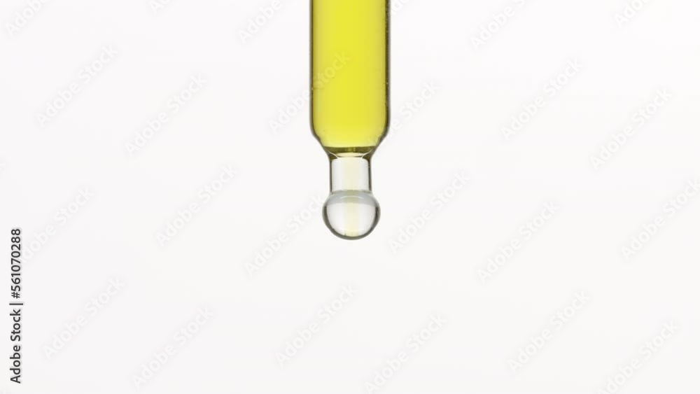 Macro shot of yellow drops are falling down from lab dropper occasionally on grey background | Abstract skin care cosmetics formulation concept Macro shot of yellow drops are falling down from lab dropper occasionally on grey background | Abstract skin care cosmetics formulation concept