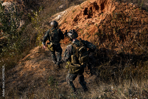 group of soldiers descend from mountain, leaving the hot spot during military operation. rear view men in military clothes with rifles. Soldiers in Camouflage on a Reconnaissance Military Mission