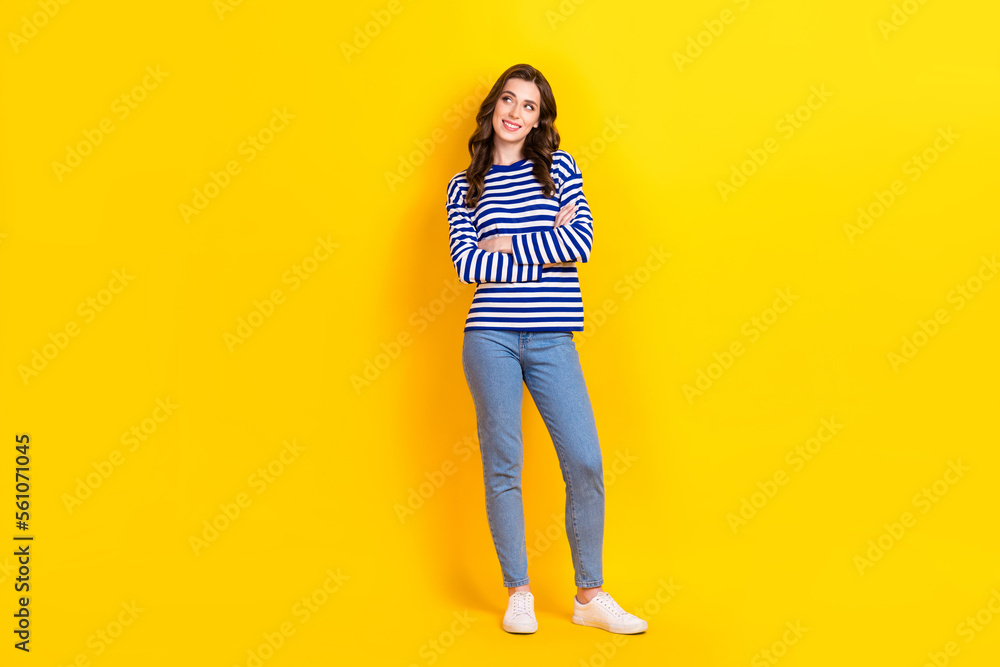Full body photo of pretty young girl folded arms look empty space dressed stylish striped outfit isolated on yellow color background Full body photo of pretty young girl folded arms look empty space dressed stylish striped outfit isolated on yellow color background