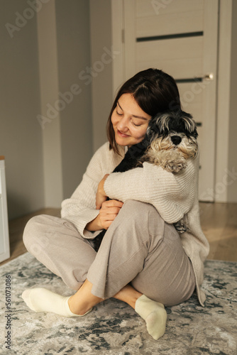 Beautiful caucasian woman with vitiligo hugging her dog miniature schnauzer breed  at home. Friendship concept