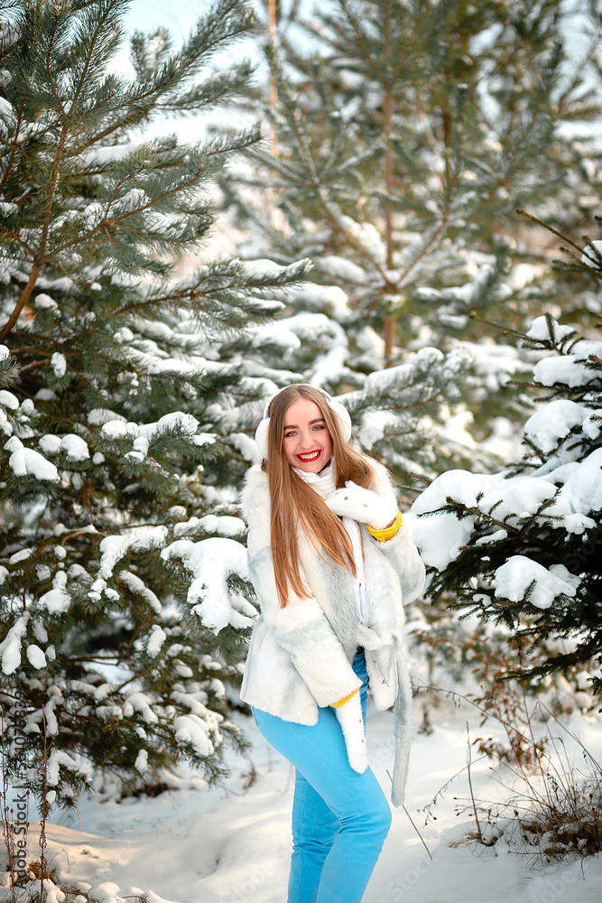 Vinnytsia, Ukraine. January 12, 2023: Portrait of a girl in winter in a white rabbit fur coat. White warm headphones. Sincere smile. Emotions
