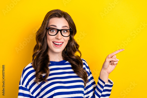 Photo of young positive excited businesswoman wear striped shirt direct finger empty space surprised good news isolated on yellow color background