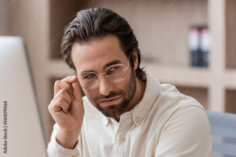 young bearded businessman in white shirt adjusting eyeglasses and looking away in office. young bearded businessman in white shirt adjusting eyeglasses and looking away in office.