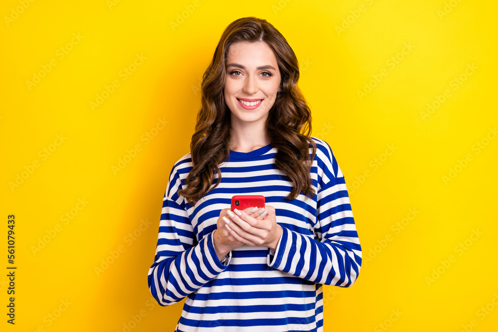 Photo of positive cheerful satisfied young lady wear striped pullover hold modern gadget chat online free wifi isolated on yellow color background Photo of positive cheerful satisfied young lady wear striped pullover hold modern gadget chat online free wifi isolated on yellow color background