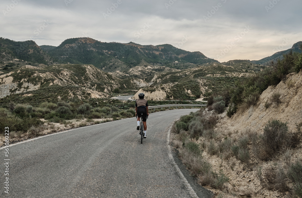 Man riding a gravel bicycle on the road in hills with mountain view, Murcia region in Spain 