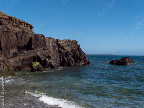 A rock among the blue sea waters. Seaside landscape, rocky mountain beside body of water.