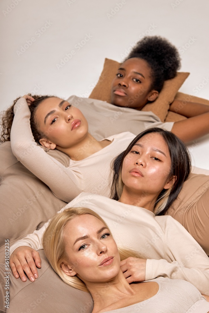 models being very close one to each other, lying on floor, expressing friendship and tolerance. attractive beautiful women in casual outfit looking relaxed. indoor shot, top view. focus on blonde models being very close one to each other, lying on floor, expressing friendship and tolerance. attractive beautiful women in casual outfit looking relaxed. indoor shot, top view. focus on blonde