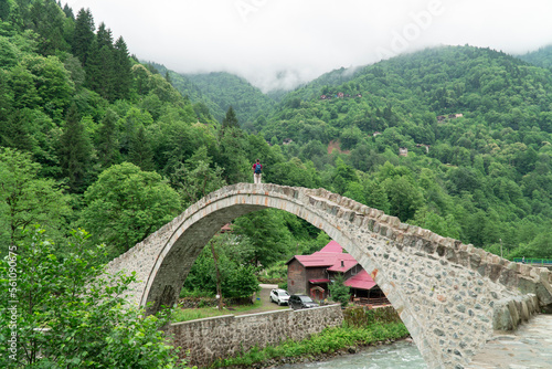 Old stone footbridge. Tourist standing on the bridge  Senyuva over the Firtina river in Camlihemsin, Rize, Turkey