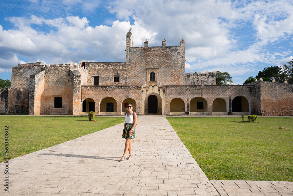 Young female tourist outside the San Bernardino Convent with the manicured, green lawn in Valladolid, Mexico.