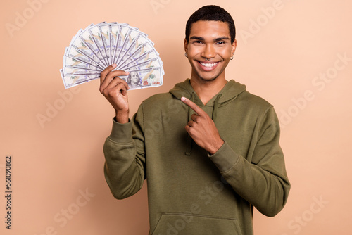 Photo of young rich wealthy shopaholic guy khaki sweatshirt direct finger his savings for new clothes sale isolated on beige color background