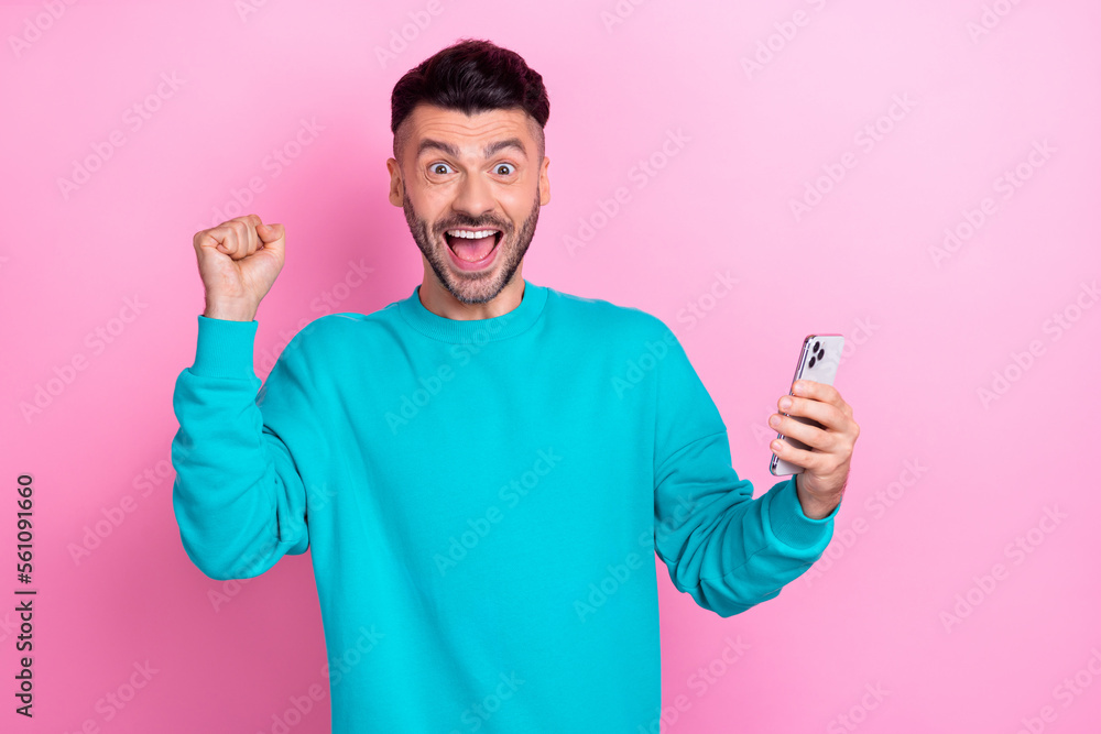 Photo of excited crazy person raise fist shout yes hooray hold telephone isolated on pink color background Photo of excited crazy person raise fist shout yes hooray hold telephone isolated on pink color background