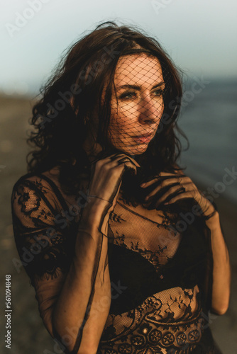 Portrait woman in sexy black dress walking with on the winter beach