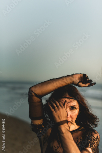 Portrait woman in sexy black dress walking with on the winter beach