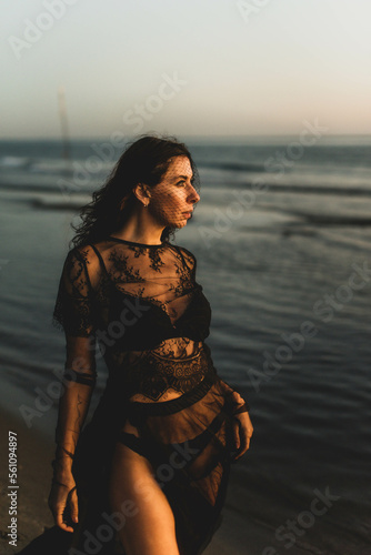 Portrait woman in sexy black dress walking with on the winter beach
