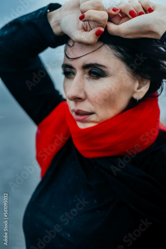 Portrait woman in black dress walking with red scarf on the winter beach