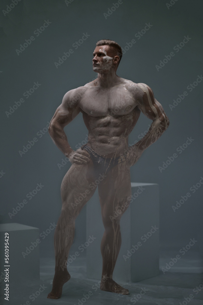 Muscular shirtless male athlete bodybuilder on a grey background