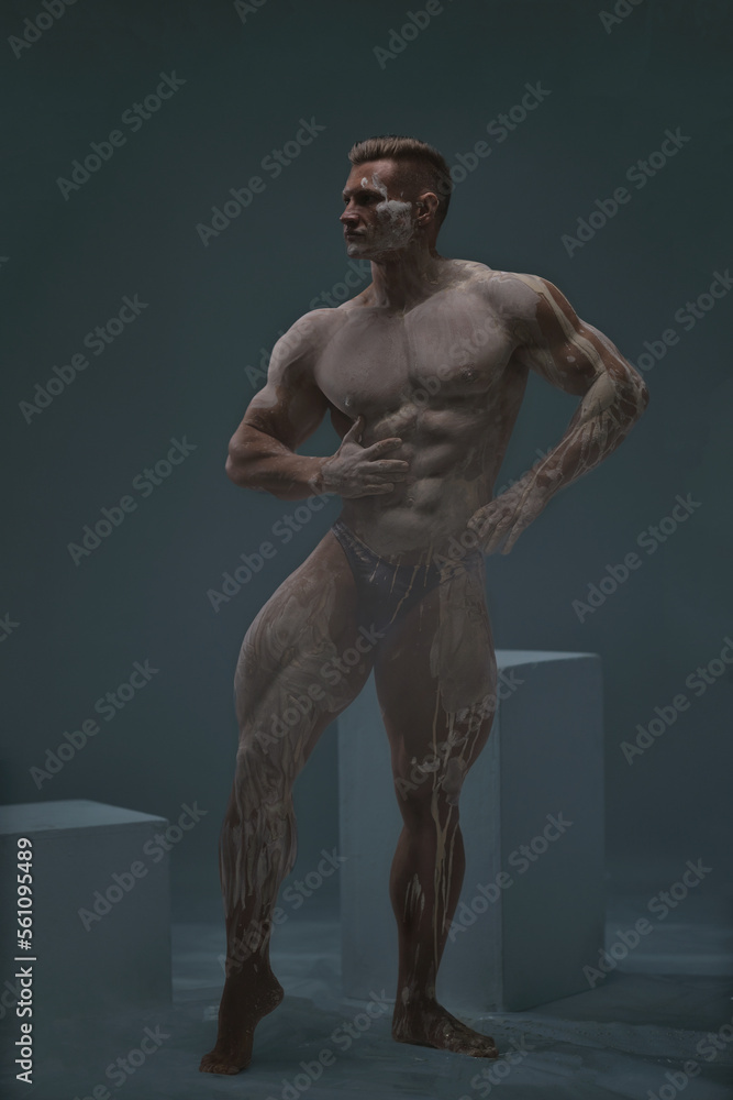 Muscular shirtless male athlete bodybuilder on a grey background Muscular shirtless male athlete bodybuilder on a grey background