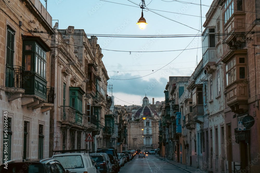 Empty street in Malta with typical balconies and architecture and a church