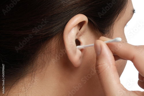 Woman cleaning ear with cotton swab on white background, closeup