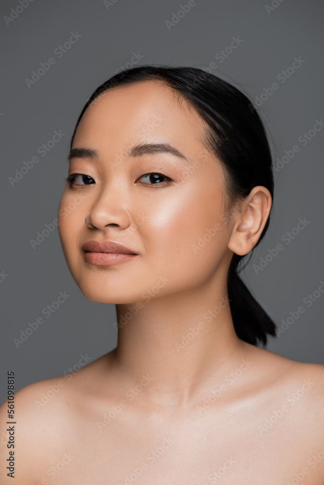 Young asian woman with naked shoulders looking at camera isolated on grey. Young asian woman with naked shoulders looking at camera isolated on grey.