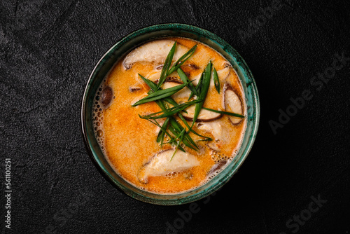 Tom yum kung soup with mushroom and spoon on black bacground